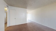 This single-floor residential unit offers a practical and well-organized layout designed for comfortable everyday living. The spacious living area features warm-toned carpeting and clean white walls beneath a textured popcorn ceiling, creating a neutral and versatile backdrop. Natural light filters in through windows, and a front entry door opens directly into the living space.

The kitchen is efficiently arranged in a U-shaped configuration, showcasing white cabinetry with ample storage extending to the upper walls, a white electric range, dishwasher, and refrigerator. Wood-look flooring grounds the kitchen, and a sliding glass door provides direct access to an outdoor deck, filling the space with additional natural light.

The bedrooms are carpeted and generously sized, each featuring windows that bring in outside light. The primary bedroom includes dual closets, offering substantial storage. Additional bedrooms are bright and open, with neutral walls and textured ceilings consistent throughout the unit.

Two bathrooms serve the residence. One features a vanity with under-cabinet storage, a lighted mirror, and wood-look flooring. The second includes a full tub-shower combination with white tile surround, a toilet, and a vanity — both finished in a clean, neutral palette that keeps the spaces feeling fresh and functional.