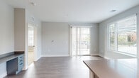 Located at 750 E Broad St in Columbus, Ohio, this single-floor unit offers a clean, contemporary design throughout. The open living area is bathed in natural light, courtesy of large windows with blinds and sliding glass doors that lead to a private balcony with outdoor views of mature trees and the surrounding neighborhood. Durable wood-look flooring runs through the main living spaces, while plush carpet adds warmth to the bedrooms.

The kitchen is well-equipped with stainless steel appliances including a range, microwave, and refrigerator, complemented by gray cabinetry, quartz-style countertops, a subway tile backsplash, a built-in wine rack, and a central island for additional prep space. A hallway connects the main living areas to the private quarters, where bedrooms feature generous natural light and walk-in closets with built-in shelving.

The bathrooms stand out with bold teal accent walls, white vanities with neutral countertops, black hardware accents, and light wood-look flooring, lending a vibrant yet cohesive aesthetic. A dedicated laundry closet with a stacked washer and dryer adds everyday convenience. Throughout the unit, recessed lighting, black hardware details, and a neutral gray color palette create a modern, cohesive atmosphere.