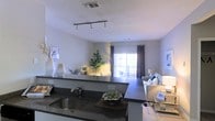 Located at 1455 Washington Blvd in Stamford, Connecticut, this single-floor residence offers a thoughtfully designed open-concept layout that seamlessly connects the kitchen and living areas. The kitchen features dark granite countertops with a stainless steel sink, providing both style and functionality. A breakfast bar creates a natural transition into the living space, making it ideal for entertaining or everyday living. Track lighting overhead ensures the kitchen is well-illuminated, while the textured ceiling adds a subtle architectural detail throughout. The living area is generously proportioned, bathed in natural light streaming through a large window dressed with dark curtains that offer contrast and privacy. A sliding glass door leads to a private balcony, extending the living space outdoors and allowing for abundant natural light. The neutral color palette throughout — soft whites and warm grays — creates a clean, modern ambiance that feels both welcoming and versatile. The open flow between spaces enhances the sense of roominess, making this residence a comfortable and contemporary home in the heart of Stamford.