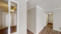 This single-story residence offers a clean, functional layout with consistent design choices carried throughout. Wood-look plank flooring runs through the living areas, bedrooms, and hallways, providing a warm and cohesive aesthetic. Crown molding accents the ceilings in multiple rooms, adding a refined architectural detail against neutral gray and beige wall tones.

The kitchen is well-equipped with ample white cabinetry, light countertops, and black appliances including a gas range, built-in microwave, and dishwasher. A double-basin sink sits beneath a standard faucet, and the space offers generous storage and counter workspace.

The living and dining areas are open and airy, benefiting from natural light through slatted blinds. The textured ceilings and crown molding continue the consistent finish work seen throughout the home.

The bedrooms are comfortably sized with neutral walls, crown molding, and natural light from windows. One bedroom features a large double-door closet with built-in shelving, while another includes an adjacent walk-in closet area. Ceiling fans provide additional comfort.

The bathrooms are cleanly finished with white vanities, mirrors with lighting, and a tub-shower combination. The layout connects efficiently to the bedroom areas, making daily routines convenient and straightforward.