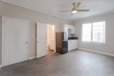 Located at 5640 Santa Monica Blvd in the heart of Los Angeles, this single-floor studio unit offers a practical and efficiently designed living space. The main room features wood-look plank flooring throughout, neutral-toned walls with textured finishes, and crown molding that adds a subtle architectural detail. A ceiling fan with an integrated light fixture provides both ventilation and ambient lighting, while a window with vertical blinds allows natural light to filter in and offers views of the surrounding neighborhood.

The kitchenette is well-appointed with sleek white cabinetry — including both upper and lower cabinet storage — dark countertops, a stainless steel sink, and a full-size black refrigerator. The clean, modern cabinetry design maximizes storage within the compact space.

The bathroom is bright and functional, finished in white throughout. It includes a full-size bathtub with an overhead shower, chrome fixtures, and a towel ring, maintaining a clean and minimal aesthetic.

The open layout of the main living area provides flexibility for furniture arrangement, making the space adaptable to a variety of needs. Overall, this unit presents a clean, move-in-ready living environment in a central Los Angeles location.
