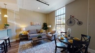 Located at 429 Valley St in Providence, Rhode Island, this single-floor residence offers a thoughtfully designed layout with a seamless flow between living, dining, and kitchen spaces. The living area is a standout, boasting soaring ceilings and expansive floor-to-ceiling windows that flood the room with natural light and offer views of the surrounding neighborhood. Warm neutral tones and hardwood-style flooring carry throughout, creating a cohesive and inviting ambiance.

The kitchen is well-equipped with white cabinetry, granite countertops, stainless steel appliances, and a breakfast bar with seating — ideal for both casual dining and entertaining. An adjacent half-bath features granite counters and wood-look tile flooring, with an exposed structural column adding a distinctive architectural touch.

Both bedrooms are comfortably sized with plush carpeting and recessed lighting. The primary bedroom includes a walk-in closet, while a full bathroom serves the space with a combined tub and shower, a white vanity with granite countertop, and hardwood-style flooring. The overall design balances modern finishes with a warm, residential character throughout.