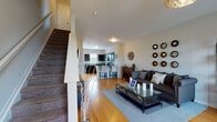 This three-floor home is thoughtfully designed to balance open, communal living spaces with private retreats. The main level showcases warm hardwood flooring throughout, anchoring an open-concept layout where the living room flows seamlessly into the kitchen and dining area. The living room is generously proportioned, filled with natural light from multiple windows, and features neutral walls that complement the space's contemporary aesthetic. A convenient half bath with a pedestal sink is also located on this level.

The kitchen is well-equipped, featuring dark espresso cabinetry, gray countertops, a kitchen island with bar seating, and black appliances including a range, microwave, and dishwasher. A door from the kitchen provides additional access to the exterior, enhancing functionality.

One of the upper floors hosts a dedicated home office with carpeted flooring, large built-in display cabinetry, and ample workspace. A comfortable bedroom on this level offers plush carpeting, a generously sized window with natural light, and a relaxed, welcoming atmosphere.

Throughout all three floors, the home maintains a cohesive design with neutral tones, clean lines, and a functional layout suited to a variety of lifestyles.