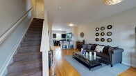 This three-floor home is thoughtfully designed to balance open, communal living spaces with private retreats. The main level showcases warm hardwood flooring throughout, anchoring an open-concept layout where the living room flows seamlessly into the kitchen and dining area. The living room is generously proportioned, filled with natural light from multiple windows, and features neutral walls that complement the space's contemporary aesthetic. A convenient half bath with a pedestal sink is also located on this level.

The kitchen is well-equipped, featuring dark espresso cabinetry, gray countertops, a kitchen island with bar seating, and black appliances including a range, microwave, and dishwasher. A door from the kitchen provides additional access to the exterior, enhancing functionality.

One of the upper floors hosts a dedicated home office with carpeted flooring, large built-in display cabinetry, and ample workspace. A comfortable bedroom on this level offers plush carpeting, a generously sized window with natural light, and a relaxed, welcoming atmosphere.

Throughout all three floors, the home maintains a cohesive design with neutral tones, clean lines, and a functional layout suited to a variety of lifestyles.