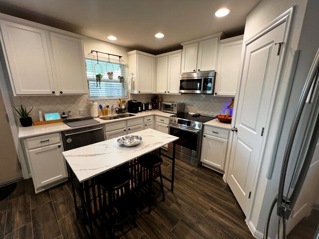 Big kitchen with lots of counter space, a variety of new appliances, and large pantry and fridge. - 9611 Morning Iris Dr