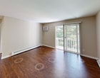 Located at 1640 S Greenfield Circle Northeast in Grand Rapids, this 650-square-foot apartment offers a practical and comfortable single-floor layout with 2 bedrooms and 1 bathroom. The living room features rich hardwood-style flooring, a wall-mounted AC unit, a baseboard heating system, and a sliding glass door that opens to a private balcony overlooking a lush, tree-lined outdoor area. The kitchen is efficiently designed with white cabinetry, granite-style countertops, a double stainless steel sink, and white appliances including a range and dishwasher. Both bedrooms are carpeted and equipped with ceiling fans and baseboard heaters. The primary bedroom measures 150 square feet and includes a closet with built-in shelving, while the second bedroom features a window with outdoor views and its own closet. The full bathroom is finished with a granite-style vanity countertop, a tub-shower combination with a curtain rod, and hardwood-style flooring. Additional storage is provided via a closet near the entryway in the main living area. Neutral, warm-toned walls throughout create a cohesive and inviting ambiance across the entire unit.