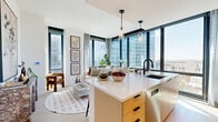 Located at 12 Church Street in New Rochelle, NY, this thoughtfully designed two-bedroom, two-bathroom residence offers a sleek, modern living experience across a single floor. The open-concept kitchen and living area serves as the heart of the home, anchored by a central island with a crisp white quartz countertop and warm golden cabinetry. Stainless steel appliances, a built-in pantry, and ample upper cabinetry round out the well-appointed kitchen. Light hardwood flooring flows seamlessly throughout, complementing the clean white walls and creating a bright, airy atmosphere. The living area is framed by expansive floor-to-ceiling windows on two sides, flooding the space with natural light and offering sweeping urban views of the New Rochelle skyline. Both bedrooms continue the floor-to-ceiling window motif, providing each room with generous natural light and city vistas. The two bathrooms are finished in elegant marble-style tile from floor to ceiling, with one featuring a glass-enclosed walk-in shower and the other a soaking tub. A dedicated laundry area, multiple closets, and well-proportioned hallways add to the home's practical appeal. The overall ambiance is clean, contemporary, and luminous.