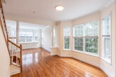 Located at 2 Charley's Pl, Unit 2, in Bay Shore, NY, this multi-level residence spans three floors and offers a thoughtfully designed layout with a variety of quality finishes throughout. The main living level immediately impresses with gleaming hardwood floors that extend across a spacious open living and dining area. A standout feature is the curved bay window arrangement, which floods the space with natural light and frames attractive views of the surrounding greenery. Crown molding and decorative columns add architectural elegance to the living area. The kitchen is well-equipped, featuring warm honey-toned wood cabinetry, granite-style countertops, stainless steel appliances including a range and dishwasher, and a corner sink. A convenient half bath with light tile flooring and a window is also found on this level. The staircase, finished with rich hardwood treads and a classic wood railing, connects all three floors. Upper-level rooms feature plush wall-to-wall carpeting, ample natural light from bay and standard windows, and generous closet space including a walk-in closet with wire shelving. The lower level provides additional functional space. Throughout the home, recessed lighting, crown molding, and clean white walls contribute to a bright, polished, and inviting atmosphere.