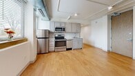 Located at 7150 Montview Blvd in Denver's Park Hill neighborhood, this 2-bedroom, 1-bathroom unit offers a well-organized single-floor layout with a modern industrial aesthetic. Exposed ductwork and track lighting run throughout the unit, lending a loft-like character to the clean white walls and warm hardwood-style flooring found in every room.

The kitchen is equipped with a full suite of stainless steel appliances, including a refrigerator, range, microwave, and dishwasher. Gray shaker-style cabinetry pairs with a white subway tile backsplash and light countertops, creating a contemporary, functional workspace. Large windows admit natural light and overlook the surrounding neighborhood.

The spacious primary bedroom features a generous open closet with built-in railing, providing ample storage. Both bedrooms include distinctive bay windows that frame outdoor tree views, filling the rooms with natural light. The second bedroom also benefits from an open closet area with built-in shelving.

The bathroom is clean and well-appointed, featuring a full tub-shower combo with built-in shelving, a single-sink vanity with white cabinetry, and hardwood-style flooring. A hallway connects the rooms efficiently, completing this compact yet thoughtfully designed unit.