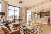 Located in Atlanta's prestigious Buckhead neighborhood (30326), this single-floor residence showcases a thoughtfully designed open-concept layout with contemporary finishes throughout. Dramatic floor-to-ceiling windows are a defining architectural feature, flooding the living spaces with natural light while framing striking views of the surrounding Atlanta skyline and cityscape.

The expansive living and dining area centers around the oversized windows, creating a seamless connection between interior comfort and urban scenery. Light hardwood flooring runs throughout the main living spaces, complementing the neutral tones of the walls and contributing to a bright, airy ambiance.

The kitchen is appointed with warm wood cabinetry, stainless steel appliances including a full-size refrigerator, gas range, and microwave, as well as a large white quartz island with bar seating and striking pendant lighting above.

Each bedroom benefits from large windows offering city and courtyard views, plush carpeting, and generous proportions. The bathrooms feature wood-grain floating vanities with white quartz countertops, framed mirrors, glass-enclosed showers, and tile flooring, providing a clean, modern aesthetic throughout.