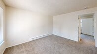 Located at 401 Ratcliff Dr SE in Salem, Oregon, this one-bedroom, one-bathroom unit offers an efficient and practical single-floor layout. The kitchen is well-equipped with ample white cabinetry, generous counter space, wood-look flooring, and full appliances including a range, refrigerator, and dishwasher — all finished in a clean, cohesive white palette. A window provides natural light, making the space feel open despite its compact footprint. The living area transitions seamlessly from the kitchen, with a defined carpeted zone that provides a comfortable, warm feel underfoot. The bedroom features plush carpet, a textured ceiling, and a baseboard heating unit, offering a cozy and functional retreat. Neutral wall tones throughout keep the space feeling bright and versatile. The bathroom includes a wide vanity with a large mirror, built-in lighting, white cabinetry with storage drawers, and wood-look flooring that ties back to the kitchen aesthetic. A dedicated utility room adds practical storage and functional space. Overall, the unit presents a clean, no-frills design well-suited for straightforward, comfortable everyday living.