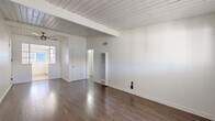 Located at 4115 Palmwood Dr in Los Angeles, CA, this one-bedroom, one-bathroom unit offers a thoughtfully laid-out single-floor plan. The combined kitchen and living area serves as the heart of the home, featuring rich, dark wood-look flooring that runs throughout the space and a distinctive white-painted beamed ceiling that adds architectural character and a sense of openness. Natural light filters in through the windows, keeping the living area bright and airy, while a wall-mounted heating unit provides functional climate control.

The bedroom is a well-proportioned private retreat, continuing the same warm wood-look flooring. It features a mirrored sliding closet door paired with upper cabinet storage, maximizing vertical space and enhancing the sense of roominess. Additional closet spaces are distributed throughout the unit, offering generous storage options.

The bathroom is finished in clean, all-white tones with light wood flooring, a combination tub and shower, a vanity with ample countertop space, and a frosted privacy window that allows natural light while maintaining seclusion. Two hallways connect the spaces efficiently. The overall ambiance is clean, minimal, and bright — well-suited for comfortable everyday living in the heart of Los Angeles.