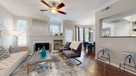 This three-floor home offers a thoughtfully designed interior with a cohesive neutral palette and warm hardwood flooring that flows throughout the main living areas. The open-concept living room serves as the heart of the home, anchored by a classic fireplace with a clean white surround and framed by multiple windows fitted with plantation shutters and curtain panels that invite generous natural light. Crown molding and ceiling fans add refined architectural detail to the space.

The living area connects seamlessly to a dedicated dining space, which features a stylish pendant light overhead and direct access to the kitchen. The kitchen is equipped with white cabinetry, granite countertops, stainless steel appliances, and rich hardwood flooring, offering both function and visual appeal.

The bedrooms are carpeted for comfort and feature vaulted ceilings, ceiling fans, and ample closet space. Each room is well-lit with large windows that enhance the sense of openness. Two bathrooms serve the home—one with a frameless glass shower enclosure and granite vanity, and another with a full soaking tub, white tile surround, and matching cabinetry. Together, the spaces present a balanced blend of classic design and practical living across all three floors.