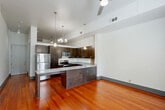 Located at 427 Josephine Street in New Orleans' historic Garden District, this thoughtfully designed unit offers a well-appointed single-floor layout comprising a kitchen and a full bathroom. Rich, warm-toned hardwood flooring runs throughout, anchoring the space with a sense of character and warmth.

The kitchen is a standout feature, boasting an expansive granite-topped peninsula ideal for dining or prep work. Dark espresso cabinetry provides ample storage and contrasts elegantly with stainless steel appliances, including a full-size refrigerator, range, and built-in microwave. Soaring ceilings with pendant lighting and a chandelier lend an airy, loft-like quality to the space.

The main living area benefits from large glass doors that flood the room with natural light and offer a view of lush greenery outside. A striking exposed brick accent wall adds a nod to the building's historic character, blending seamlessly with the contemporary finishes.

The bathroom is clean and classic, featuring a tub-shower combination, a granite-topped vanity with storage cabinetry, a large mirror, and charming black-and-white mosaic tile flooring. Together, the elements of this space create a balanced blend of historic New Orleans charm and modern urban living.