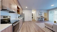 This thoughtfully designed one-bedroom, one-bathroom unit at 849 E Magnesium in Spokane, Washington offers a modern open-concept layout that seamlessly connects the kitchen, dining, and living areas. The kitchen is outfitted with warm wood-tone cabinetry, white quartz countertops, a full suite of stainless steel appliances including a range, dishwasher, built-in microwave, and refrigerator, plus a deep undermount sink. Light-toned luxury vinyl plank flooring flows throughout the main living areas, creating a clean, cohesive aesthetic. The living room is bright and welcoming, featuring large sliding glass doors that flood the space with natural light and open to a private outdoor patio. A wall-mounted mini-split system provides efficient climate control. An in-unit stacked washer and dryer adds everyday convenience. The bedroom features plush carpet, a bold accent wall, and a generous window with outdoor views. The bathroom is finished with warm wood vanity cabinetry, a grey quartz countertop, undermount sink, and a full mirror. A dedicated closet completes this well-appointed unit, ideal for comfortable, low-maintenance living in north Spokane.