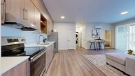 This thoughtfully designed one-bedroom, one-bathroom unit at 849 E Magnesium in Spokane, Washington offers a modern open-concept layout that seamlessly connects the kitchen, dining, and living areas. The kitchen is outfitted with warm wood-tone cabinetry, white quartz countertops, a full suite of stainless steel appliances including a range, dishwasher, built-in microwave, and refrigerator, plus a deep undermount sink. Light-toned luxury vinyl plank flooring flows throughout the main living areas, creating a clean, cohesive aesthetic. The living room is bright and welcoming, featuring large sliding glass doors that flood the space with natural light and open to a private outdoor patio. A wall-mounted mini-split system provides efficient climate control. An in-unit stacked washer and dryer adds everyday convenience. The bedroom features plush carpet, a bold accent wall, and a generous window with outdoor views. The bathroom is finished with warm wood vanity cabinetry, a grey quartz countertop, undermount sink, and a full mirror. A dedicated closet completes this well-appointed unit, ideal for comfortable, low-maintenance living in north Spokane.