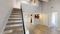 Located at 12712 Coeur du Monde Ct in Maryland Heights, Missouri, this two-story residence is defined by dramatic vaulted ceilings that create a sense of openness and volume from the moment you enter. The main level features light wood-style flooring that flows throughout, anchored by a spacious living area with a sleek fireplace and large windows fitted with blinds that allow natural light to filter in. A staircase with black metal railings ascends to the upper level, adding a contemporary architectural detail to the interior.

The kitchen is well-appointed with rich dark cabinetry, granite-style countertops, stainless steel appliances including a refrigerator, range, and built-in microwave, and a double sink. A peninsula connects the kitchen to the adjacent dining and living areas, supporting an open-concept layout.

Bedrooms feature wood-style flooring, neutral tones, and natural light from windows. One bedroom includes a built-in closet with bifold doors. The bathroom offers a full tub and shower combination with clean, light surrounds and chrome fixtures.

The upper level loft benefits from a skylight and vaulted ceiling, creating a bright, flexible space that overlooks the main living area below via an open railing.