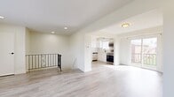 This thoughtfully designed one-bedroom, one-bathroom residence offers a clean, modern aesthetic throughout its efficiently arranged floor plan. Light gray wood-style flooring flows seamlessly across the entire level, lending a cohesive and airy feel to every room.

The main living area is open and welcoming, with recessed lighting and neutral white walls that maximize the sense of space. A decorative wrought-iron staircase railing serves as a subtle architectural accent, connecting the unit to the level below via a staircase with dark wood treads and a clean white handrail.

The kitchen is well-appointed with crisp white shaker cabinets extending to the ceiling, a classic white subway tile backsplash, and a full suite of stainless steel appliances including a refrigerator, dishwasher, and range. A window above the sink allows natural light to brighten the workspace, while a sliding door nearby provides additional light and outdoor access.

The spacious primary bedroom offers ample room for furnishings, with recessed lighting, a window with blinds for natural light, and direct access to the bathroom. The bathroom features a soaking tub with elegant marble-style tile surrounds, a white vanity with a clean countertop, and a large mirror, creating a serene and polished atmosphere throughout.