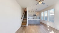 Located on Fullerton Drive in Huntsville, Alabama, this contemporary two-story home offers a thoughtfully designed layout across two floors. The main level features an open-concept living and kitchen area bathed in natural light from multiple windows, with light-toned hardwood-style flooring flowing throughout. The kitchen is a standout, showcasing gray shaker-style cabinetry, a herringbone tile backsplash, stainless steel appliances, and a large center island with a white quartz countertop and double sink, illuminated by stylish pendant lighting. A ceiling fan completes the airy living area, while a staircase with warm wood treads and a handrail leads to the upper level. Upstairs, the spacious primary bedroom offers a generous closet and ample natural light through slatted blinds, while the second bedroom provides a comfortable and bright retreat. Both bathrooms are finished with gray cabinetry, white quartz countertops, large mirrors, and tub-shower combinations. A dedicated laundry area houses a full-size washer and dryer with overhead shelving for added convenience. Clean white walls and consistent flooring throughout create a cohesive, modern ambiance ideal for comfortable everyday living.