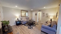 This single-story home offers a thoughtfully designed layout with consistent neutral tones and modern finishes throughout. The living room serves as the central gathering space, featuring light wood-look flooring, recessed lighting, and a textured ceiling. A large ornate-framed mirror anchors one wall, enhancing the sense of space, while an open flow connects to an additional sitting or dining area with a ceiling fan and natural light.

The kitchen is efficiently laid out with white cabinetry, granite-look countertops, a double-basin sink, and a full suite of appliances including a gas range and dishwasher. A skylight-style ceiling fixture provides bright, even illumination, complemented by a window above the sink.

The primary bedroom is generously sized, accommodating a four-poster bed and matching dark wood furniture. Soft carpeting, a textured ceiling, and a walk-in closet contribute to its comfortable feel. A second bedroom also features carpet and large windows dressed with sheer curtains, allowing ample natural light.

The bathrooms include a full bath with a tub-shower combination and a separate vanity area featuring a wide white countertop, a large mirror, and wood-look flooring. The overall ambiance is clean, neutral, and move-in ready.