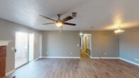 Located at 715 Rice Rd in Ridgeland, Mississippi, this single-story home offers a well-designed layout with a range of updated features. The spacious living room is a standout, showcasing light wood-look flooring, a classic brick fireplace with a white mantel, a ceiling fan with integrated lighting, and a sliding glass door that opens to an outdoor patio area, filling the space with natural light. The kitchen is thoughtfully appointed with white cabinetry, light stone-look countertops, a herringbone-patterned tile backsplash, stainless steel appliances including a refrigerator and dishwasher, and a peninsula that provides additional prep space and a natural divide between the kitchen and living areas. A secondary living or dining area adjacent to the kitchen features matching wood-look flooring and another ceiling fan. The bedrooms are carpeted for comfort, with ceiling fans and windows fitted with blinds. The bathrooms are finished with wood-look tile flooring, white vanities, and light stone countertops; one bathroom includes a tub-shower combination. A dedicated laundry room with upper white cabinetry and a window completes this well-appointed home.