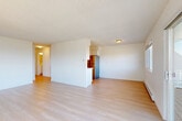Located at 480 S State St in Bellingham, WA, this 2-bedroom, 1-bathroom residence offers a comfortable and functional layout across a single floor. Light-toned hardwood-style flooring runs throughout, complementing the clean white walls and textured ceilings that give the space a bright, airy feel. The open living area flows into a combined dining and kitchen space, with a well-designed galley-style kitchen featuring white shaker cabinetry, white countertops, stainless steel appliances including a refrigerator, electric range, built-in microwave, and dishwasher. A dedicated dining area sits adjacent to the kitchen for easy entertaining. The living room is bathed in natural light and opens directly onto a private balcony through sliding glass doors, offering picturesque outdoor views of the surrounding greenery and water. Both bedrooms are generously sized, well-lit by multiple windows, and serviced by baseboard heating. The bathroom includes a full tub-shower combination with clean white tile surround and modern chrome fixtures. A hallway laundry closet with a stacked washer and dryer adds in-unit convenience. Three additional closets provide ample storage throughout.