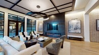 This elegantly designed single-floor space blends contemporary architecture with refined interior details to create a polished and inviting environment. The main lounge area commands attention with its bold coffered ceiling, defined by dark steel grid lines that frame inset panels — a design element that adds depth and visual structure overhead. Suspended from the center is a large circular LED pendant light, serving as a dramatic focal point that anchors the room.

Floor-to-ceiling steel-framed windows line the perimeter, flooding the space with abundant natural light and offering open views to the surrounding exterior. The warm light wood flooring grounds the room with a natural warmth that contrasts beautifully against the darker architectural accents.

A feature wall clad in deep charcoal stone houses a wide-format fireplace below a recessed flat-screen display, creating a sleek and functional centerpiece. Exposed brick walls on the adjacent side add a textural, industrial character, accented by curated artwork mounted under picture lights.

A secondary area functions as a media and kitchenette lounge, complete with dark wood cabinetry, a sink, appliances, a wall-mounted screen, and a large communal table — ideal for gatherings. The space is furnished throughout with a sophisticated mix of neutral upholstered seating, textured accent chairs, and carefully selected decorative objects.