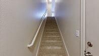 This well-designed townhome in Mill Creek, WA offers 1050 square feet of living space spread across three floors. The property features 2 bedrooms, including a primary bedroom of 130 square feet, and 2 bathrooms. The open-concept main living area combines the kitchen and living room, creating a spacious feel. The kitchen boasts honey-colored cabinetry, stainless steel appliances, and quartz countertops, with a convenient breakfast bar. The living room is enhanced by a modern fireplace and sliding glass doors leading to an outdoor area. Plush carpeting in bedrooms and living areas contrasts with durable wood-look flooring in the kitchen and bathrooms. The home includes 3 closets for ample storage, and large windows throughout provide natural light. The multi-level layout offers privacy and separation of living spaces, making this townhome ideal for comfortable modern living.