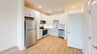 Located at 200 Brooklawn St in Farragut, TN, this thoughtfully designed one-bedroom, one-bathroom unit offers a clean, modern aesthetic throughout its single-level layout. The open-concept kitchen and living area serves as the heart of the home, featuring light hardwood-style flooring, neutral walls, and a ceiling fan that enhances the bright, airy feel. The kitchen is outfitted with crisp white shaker cabinets, light quartz countertops, a marble-style tile backsplash, and a full suite of stainless steel appliances including a refrigerator, range, over-the-range microwave, and dishwasher. Recessed lighting and a window overlooking the greenery outside add to the inviting atmosphere. The generously sized primary bedroom is carpeted for comfort and includes a large window with outdoor views and a ceiling fan, creating a serene retreat. Doors from the bedroom provide direct access to the kitchen area and the full bathroom. The bathroom features a tiled shower-tub combination with brushed nickel fixtures, hardwood-style flooring, and a clean, minimalist design. Throughout the unit, white panel doors, wide baseboards, and a consistent neutral palette lend a cohesive, polished look.