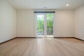 Located at 242 Dunning St in Madison, WI, this one-bedroom, one-bathroom unit offers a well-designed single-floor layout with thoughtful finishes throughout. Light wood flooring flows continuously across the entire space, creating a cohesive and bright interior.

The open-concept kitchen and living area serves as the heart of the unit. The kitchen is well-appointed with warm wood cabinetry, a tile backsplash, stainless steel appliances — including a refrigerator, microwave, and dishwasher — white countertops, and a freestanding kitchen island that provides additional prep and storage space. A linear pendant light anchors the kitchen area, while recessed lighting illuminates the full open floor plan. French doors in the living area open directly onto a private patio with a railed balcony, offering pleasant outdoor views of mature trees and the surrounding neighborhood.

The bedroom is a comfortable, sun-filled retreat with a large window, ceiling fan, and direct views to the patio. Two closets provide ample storage. The bathroom features a wood vanity with a wide white countertop, a large mirror, and an accessible layout with grab bars. A stacked washer and dryer are conveniently located adjacent to the bathroom, completing the in-unit laundry setup.