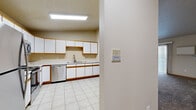 Located at 4961 44th Ave S in Fargo, North Dakota, this single-floor, 2-bedroom, 2-bathroom residence offers a practical and well-organized layout. The combined kitchen and living area forms the heart of the unit. The kitchen is equipped with abundant white cabinetry accented by warm wood trim, a stainless steel double sink, generous counter space, and a stainless steel dishwasher. Light tile flooring and a flush ceiling light fixture keep the space bright and functional. The living room features plush carpeting, a sliding glass door that floods the room with natural light and provides views of the surrounding neighborhood, and a baseboard heating system. Both bedrooms are carpeted and include baseboard heaters, with the second bedroom offering a window with neighborhood views and a ceiling light fixture. The two bathrooms each feature a tub-shower combo with clean white surrounds and light wood-tone vinyl flooring. A dedicated in-unit laundry room houses a full-size washer with overhead shelving, adding everyday convenience. A hallway connects the private spaces, and additional storage is available via a closet. Neutral wall tones and warm wood trim details carry throughout, giving the home a cohesive and inviting character.