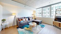 Located at 1425 Spring St in Seattle's First Hill neighborhood, this thoughtfully designed single-floor unit offers a functional and modern living experience. The open living area is a standout space, featuring an exposed concrete ceiling that lends an industrial-chic aesthetic, warm light wood flooring, and large windows that frame urban city views while filling the room with natural light. A dedicated dining nook with a bar-height table complements the living space seamlessly.

The bedroom is a calm and well-appointed retreat, featuring a sliding closet door, exposed concrete ceiling detail, and clean white walls that create a bright, restful ambiance. The bathroom is efficiently laid out with a dark wood vanity, full bathtub, and crisp white walls accented by decorative sunburst mirrors, adding a touch of personality to the space.

The unit also includes an in-unit laundry area and a closet, enhancing everyday convenience. Throughout the space, consistent light wood flooring and a neutral color palette create a cohesive and modern feel. A barn-style sliding door in the hallway adds an architectural detail that ties together the contemporary design. This well-equipped urban unit offers a practical yet stylish living environment in the heart of Seattle.