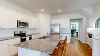 This well-appointed two-story home offers a thoughtfully designed layout across two floors, with the main level housing the primary living spaces and the upper level providing additional bedroom accommodations. The open-concept kitchen and living room form the heart of the main floor, where white shaker cabinetry, granite countertops, a subway tile backsplash, and stainless steel appliances define the kitchen. A large island with seating provides both workspace and a casual dining option. The living room features light-toned hardwood-style flooring, a ceiling fan, and sliding glass doors that open to a covered porch overlooking a fenced yard with palm trees and greenery.

A dedicated office on the main level offers natural light through blinds-fitted windows and connects conveniently to a nearby bathroom. The four bedrooms are generously proportioned, each featuring hardwood-style flooring and ceiling fans. The primary bedroom is notably spacious. Two walk-in closets provide ample storage. The four bathrooms are finished with white cabinetry, granite vanity tops, and glass-enclosed showers. Throughout the home, recessed lighting, neutral walls, and consistent flooring create a clean, cohesive aesthetic.