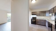 This 2-bedroom, 2-bathroom unit at 1830 N Delany Rd in Gurnee, IL offers a well-organized, single-floor layout designed for comfortable everyday living. The open kitchen-living area serves as the heart of the home, where a stylish kitchen impresses with rich dark cabinetry, granite-look countertops, a double stainless steel sink, and black appliances including a range, dishwasher, and refrigerator. The adjacent living room features light luxury vinyl plank flooring, a ceiling fan with light fixture, and a sliding glass door that opens onto a private balcony overlooking greenery — filling the space with natural light and outdoor views.

Both bedrooms continue the LVP flooring and maintain a clean, neutral palette. The primary bedroom is generously sized and includes a large double-door closet, while the second bedroom offers a window with outdoor views and a wall-mounted air conditioning unit. A dedicated walk-in closet with wire shelving provides additional storage. Both bathrooms are outfitted with tub/shower combinations featuring crisp white subway tile accented by a decorative mosaic border in warm tones and chrome fixtures. A hallway connects the rooms, creating a functional and cohesive flow throughout the residence.