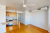 Located on the fourth floor at 875 N St NW in Washington, DC, Unit 401 is a well-designed studio that makes efficient use of its footprint. The open living area is anchored by warm hardwood flooring that runs throughout the unit, creating a cohesive and inviting atmosphere. Large corner windows flood the main living space with abundant natural light and offer expansive views of the surrounding Washington, DC rooftops and cityscape. A wall-mounted HVAC unit and ceiling fan provide year-round climate control. The kitchen is seamlessly integrated into the layout, featuring light maple cabinetry, a granite-topped breakfast bar island, track lighting, and black appliances including a refrigerator and range — making it both functional and stylish. A hallway connects the main living area to the entry and bathroom, providing a clear and logical flow throughout the unit. The bathroom is finished with warm tile flooring, tile wainscoting, a wood-toned vanity with a granite countertop, a mirrored medicine cabinet, and a glass-enclosed shower stall. The unit's clean white walls and modern finishes give it a bright, move-in-ready feel, while its elevated position offers a desirable urban perspective in the heart of the nation's capital.