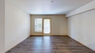 Located in Redmond, WA, this well-designed unit offers six bedrooms and two full bathrooms across a single floor, providing generous shared living space. The open-concept kitchen and living area serve as the heart of the unit, featuring dark espresso cabinetry, stainless steel appliances including a refrigerator, range, and microwave, gray countertops, and a double stainless steel sink. Wood-style laminate flooring runs throughout the entire unit, lending a warm and cohesive aesthetic. A long central hallway connects the living area to all six bedrooms, each of which is equipped with closet storage — some featuring sliding panel doors and built-in shelving racks. The bedrooms are bright and functional, with several offering windows that allow natural light to filter in. Both bathrooms are finished with patterned tile flooring, a shower-tub combination, and one includes a vanity with dark cabinetry and a large mirror. The living room is airy and open, with a door leading to an outdoor area. Recessed lighting throughout and clean neutral walls contribute to a modern, functional ambiance well-suited for shared occupancy.