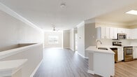 Located in Houston, TX, this two-story home offers a well-organized layout spread across two levels. The entry level is compact and functional, leading to carpeted stairs with white railings that connect to the expansive upper floor, where the majority of the living space resides. The open-concept kitchen and living room form the heart of the home, featuring light gray wood-look flooring, crown molding, and a ceiling fan that enhances airflow throughout the bright, airy space. The kitchen is equipped with white cabinetry, a stainless steel refrigerator, and a peninsula with a built-in sink and white countertop — ideal for both cooking and casual dining. Natural light filters in through windows in the living area, contributing to a warm and welcoming ambiance. Both bedrooms are finished with plush carpet, crown molding, and ceiling fans. The generously sized primary bedroom includes a walk-in closet, providing ample storage. The full bathroom features a tub-shower combination with a curved rod, a white vanity, and wood-look flooring. A dedicated laundry area with washer and dryer hookups and overhead shelving adds everyday practicality. Two closets throughout the home offer additional storage solutions.