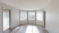 Located at 1587 S Novato Blvd in Novato, California, this single-floor unit presents a clean, contemporary design highlighted by neutral tones and an abundance of natural light throughout. The open living area features wood-style plank flooring and is lined with multiple windows dressed in vertical blinds, allowing sunlight to fill the space and creating a bright, airy atmosphere. A teal accent door adds a subtle pop of color, while a partial countertop divider connects the living space to the kitchen.

The kitchen is well-appointed with white shaker-style cabinetry, dark gray countertops, a stainless steel range with overhead ventilation, a double-basin sink, and a dishwasher — offering both functionality and a modern aesthetic.

The bedrooms are carpeted for comfort, each offering generous proportions. One bedroom benefits from a sliding glass door that opens to an outdoor view, while another includes a mirrored sliding closet. Both bedrooms provide convenient access to full bathrooms, each featuring a tub-shower combination, updated fixtures with brushed gold accents, and wood-style flooring. The overall ambiance of the unit is clean, move-in ready, and well-suited for comfortable everyday living.