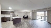 Located at 7 Colony Blvd in Wilmington, Delaware, this single-floor residence offers a thoughtfully updated interior with a clean, contemporary aesthetic throughout. The open-concept living and dining area is anchored by durable grey wood-look flooring, neutral wall tones, and a sliding glass door that floods the space with natural light while providing access to an outdoor area. A centrally positioned kitchen island with a striking marble-look countertop serves as a focal point, seamlessly connecting the kitchen to the dining and living zones. The well-appointed kitchen features dark shaker-style cabinetry, matching marble-look countertops along the perimeter, a full suite of stainless steel appliances including a range and refrigerator, and bright flush-mount lighting overhead. The bedrooms are finished with plush wall-to-wall carpeting, large windows for natural light, and include closet storage. The bathrooms are finished in a crisp, clean style with grey shaker vanity cabinetry, white quartz-look countertops, subway-tiled tub surrounds, wood-look tile flooring, and large mirrors. A dedicated entryway with a glass-panel door provides a welcoming transition into the home. The overall design is modern, cohesive, and move-in ready.