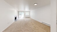 Located in Kent, Washington, this single-floor residence offers three bedrooms and two bathrooms within a well-organized and functional layout. The spacious living room serves as the heart of the home, featuring plush neutral carpeting, a tile-surround fireplace, and a sliding glass door that fills the space with natural light and provides outdoor access. The kitchen is bright and updated, showcasing white cabinetry with black hardware, light countertops, a skylight-style ceiling fixture, and black appliances including a dishwasher and electric range. Light wood-look flooring and a window overlooking greenery add to its clean, practical appeal. In-unit laundry is also present in the kitchen area. The primary bedroom is generously sized with soft carpeting and direct access to a private bathroom featuring white cabinetry and a well-lit vanity. The two additional bedrooms are carpeted and offer natural light through windows with views of surrounding trees. Both bathrooms are finished in a clean, all-white palette with tub-shower combinations, wood-look flooring, and matte black fixtures. Baseboard heating is found throughout the home, ensuring year-round comfort in this well-maintained Kent residence.