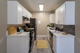 Located at 1000 Pine Ave in Redlands, California, this single-floor unit offers a thoughtfully designed layout with a clean, contemporary aesthetic throughout. Light wood-style flooring runs consistently across the living spaces, complemented by warm beige walls and crisp white baseboards that create a bright, cohesive feel.

The spacious living area features a ceiling fan, a sliding glass door that opens to a private outdoor patio, and an additional window that draws in generous natural light. A second open living or dining area also benefits from patio access via another sliding door, providing excellent indoor-outdoor connectivity.

The galley-style kitchen is well-appointed with white shaker cabinetry, white countertops, and a mosaic tile backsplash. Stainless steel appliances, including a range, refrigerator, and dishwasher, complete the functional cooking space.

The bedroom offers mirrored sliding closet doors with built-in shelving, a window overlooking the exterior, and the same wood-style flooring found throughout. The bathroom includes a white vanity with modern hardware, a combined shower and bathtub, and a high window that allows natural light while maintaining privacy. A textured ceiling is present throughout the unit, adding a classic finishing detail.