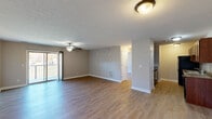 This well-appointed 2-bedroom, 2-bathroom single-floor home in New Albany, Indiana, offers a functional and comfortable layout designed for everyday living. The open-concept living and dining area is a highlight of the space, featuring warm wood-tone laminate flooring, neutral gray walls, and a ceiling fan that enhances airflow and comfort. Sliding glass doors lead to a private balcony, allowing natural light to fill the room and providing pleasant outdoor views. The kitchen is efficiently designed with rich, dark-stained cabinetry, granite-style countertops, a double-basin sink, and black appliances including a range, dishwasher, refrigerator, and built-in microwave — all set on matching laminate flooring. Both bedrooms are generously sized, each featuring wood-tone flooring, neutral tones, and windows that invite natural light and views of the surrounding greenery. The two bathrooms are clean and functional, with one featuring a full tub-shower combination. Additional conveniences include a dedicated laundry room and an impressive five closets distributed throughout, ensuring excellent storage capacity. A connecting hallway ties the layout together cohesively, making this New Albany home a practical and comfortable residence.
