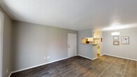 This 1-bedroom, 1-bathroom unit in Beaumont, Texas offers a well-organized single-floor layout designed for comfortable everyday living. The open living area is finished with durable wood-style flooring in a rich dark tone, neutral gray walls, and a textured ceiling that adds subtle character throughout. A sliding glass door fitted with vertical blinds leads to a private patio, allowing natural light to fill the space.

The kitchen is accessible via a pass-through counter with a tile backsplash, providing a functional connection to the living area. The galley-style kitchen is equipped with white cabinetry featuring modern hardware, a stainless steel refrigerator, an electric range, and ample counter space, making efficient use of the available area.

The bedroom is a comfortable retreat, carpeted for warmth and outfitted with a ceiling fan with integrated lighting. A window with blinds brings in natural light, and a walk-in closet provides generous storage.

The full bathroom is finished with a granite-style countertop, a framed mirror, and a tub-shower combination. Throughout the unit, the consistent use of neutral tones and updated finishes creates a cohesive and move-in-ready living environment suited for individuals or couples.