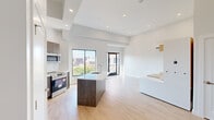 Located at 2001 Fifth Ave in Troy, NY, this single-floor unit offers a thoughtfully designed open-plan layout that maximizes its compact footprint. The main living area flows seamlessly from the kitchen into the living space, creating an efficient and cohesive environment. Elevated ceilings add a sense of vertical spaciousness, while recessed lighting throughout ensures a bright, clean aesthetic.

The kitchen is a standout feature, equipped with stainless steel appliances including a refrigerator, electric range, and microwave. Dark wood cabinetry contrasts with a marble-style tile backsplash and a central island with a white quartz countertop and integrated sink. Light hardwood flooring runs throughout the main living area, enhancing the modern, airy feel.

The living area includes built-in shelving and cabinetry with warm wood accents, a wall-mounted HVAC unit, and access to a balcony. Large windows bring in abundant natural light and offer views of the surrounding Troy cityscape.

The bathroom features dark marble-style tile flooring, a frameless glass walk-in shower, a floating white vanity with a quartz countertop, an undermount sink, and a well-lit mirror, completing the unit's clean, contemporary design.