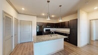 Located at 1803 W Ennis Ave in Ennis, Texas, this well-appointed one-bedroom, one-bathroom residence spans a single floor and offers a thoughtfully designed layout across its various rooms. The kitchen serves as a central highlight, featuring rich dark cabinetry paired with granite countertops, a central island with a double stainless steel sink, and stylish pendant lighting overhead. Black appliances — including a refrigerator, range, and built-in microwave — complete the kitchen's cohesive, modern aesthetic. Light wood-style flooring runs throughout the main living areas, adding warmth and continuity to the space. The entrance opens into an accessible layout that connects the kitchen and living room with ease, supported by a hallway leading to additional rooms. The bedroom offers soft carpeted flooring, a ceiling fan, multiple windows that invite natural light, and access to generous closet storage — with four closets distributed throughout the unit. The bathroom is clean and functional, showcasing granite-topped dark vanity cabinetry, a tub-shower combination, and light hardwood-style flooring. A dedicated laundry area and a private patio round out the home's practical amenities, making this residence a complete and comfortable living space.