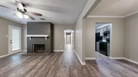 Located at 3803 Morrison Dr in Monroe, Louisiana, this single-story home offers four bedrooms, two bathrooms, and two distinct living areas within a well-utilized floor plan. Throughout the home, durable wood-look plank flooring provides a cohesive aesthetic, complemented by neutral taupe walls and white baseboards that create a clean, consistent backdrop.

The main living room serves as a focal point of the home, featuring a full-height gray brick fireplace with a white mantel, a ceiling fan, and an arched window that allows natural light to fill the space. A hallway connects the living areas to the four bedrooms, each of which features the same wood-look flooring, textured ceilings, and ceiling fans. The bedrooms offer comfortable proportions, with the primary bedroom providing a generous amount of space.

The kitchen is equipped with gray cabinetry, dark granite-style countertops, a black double-basin sink with a matte black faucet, and black appliances including a dishwasher. The two bathrooms feature gray vanities with vessel or undermount sinks, dark countertops, louvered mirrors, and a full tub-shower combination. Textured ceilings are consistent throughout the home, adding a classic residential character to every room.