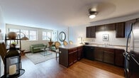 Located at 2275 Snelling Ave N in Roseville, MN, this one-bedroom, one-bathroom unit offers a well-organized, single-floor layout designed to maximize every square foot. The open-concept living and kitchen area forms the heart of the space, where warm hardwood flooring flows throughout. The kitchen is outfitted with rich dark cabinetry, black appliances including an electric range, dishwasher, microwave, and refrigerator, complemented by a peninsula counter that doubles as a dining and prep area. The living room benefits from multiple windows that invite generous natural light, creating a bright and welcoming ambiance. The bedroom is a comfortable retreat, featuring carpeted flooring, a double-door closet, and a window that provides additional natural light and outdoor views. The bathroom includes a clean, full-size soaking tub with tiled surround. A hallway connects the main living spaces to the bedroom and bathroom, contributing to an efficient and logical floor plan. Overall, the unit presents a functional and cohesive design with consistent finishes throughout, making it a practical residence in a convenient Roseville location.