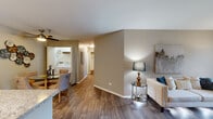 Located on N Oakhurst Dr in Aurora, Illinois, this well-appointed single-floor residence offers a cohesive blend of modern finishes and practical design throughout. The open-concept living area is anchored by rich wood-style flooring, neutral warm-toned walls, and a sliding glass door that fills the space with natural light while providing access to an outdoor area. The living room offers generous space for entertaining, complemented by ceiling fans that enhance comfort throughout.

The kitchen is a standout feature, showcasing white shaker-style cabinetry with black hardware, granite-look countertops, a subway tile backsplash, and a full suite of stainless steel appliances including a refrigerator, electric range, and microwave. A double-basin sink with a matte black faucet adds a contemporary touch.

Adjacent to the living area, the dining space is conveniently positioned next to an in-unit laundry closet housing a full-size washer and dryer. The bedrooms are carpeted for comfort, each featuring ceiling fans and ample room for furnishings. The primary bedroom includes access to a dedicated bathroom, which features a full soaking tub and shower combination. A second bedroom offers equal comfort with neutral tones and generous wall space. The layout is efficient and functional, making this residence a comfortable and stylish place to call home.