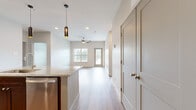 This thoughtfully designed 2-bedroom, 2-bathroom residence offers a comfortable and functional single-floor layout. The open-concept kitchen and living area serves as the heart of the home, featuring a large granite-topped island with pendant lighting, rich dark wood cabinetry, a subway tile backsplash, and stainless steel appliances. Light wood-style flooring runs throughout the main living area, enhancing the bright, airy atmosphere. The living room is highlighted by a ceiling fan, natural light from a window, and direct access to an outdoor balcony with views of surrounding greenery.

Both bedrooms are finished with plush carpet, ceiling fans, and windows that bring in natural light. The primary bedroom is generously sized and is complemented by a spacious walk-in closet with wire shelving on two walls, offering ample storage. A second closet provides additional organization space.

The primary bathroom is well-appointed with a dual-sink granite vanity, dark wood cabinetry with brushed nickel hardware, a soaking tub with white subway tile surround, and warm-toned sconce lighting. The entrance provides convenient access to the main living area and kitchen, completing this efficiently designed and modern residence.