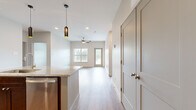 This thoughtfully designed 2-bedroom, 2-bathroom residence offers a comfortable and functional single-floor layout. The open-concept kitchen and living area serves as the heart of the home, featuring a large granite-topped island with pendant lighting, rich dark wood cabinetry, a subway tile backsplash, and stainless steel appliances. Light wood-style flooring runs throughout the main living area, enhancing the bright, airy atmosphere. The living room is highlighted by a ceiling fan, natural light from a window, and direct access to an outdoor balcony with views of surrounding greenery.

Both bedrooms are finished with plush carpet, ceiling fans, and windows that bring in natural light. The primary bedroom is generously sized and is complemented by a spacious walk-in closet with wire shelving on two walls, offering ample storage. A second closet provides additional organization space.

The primary bathroom is well-appointed with a dual-sink granite vanity, dark wood cabinetry with brushed nickel hardware, a soaking tub with white subway tile surround, and warm-toned sconce lighting. The entrance provides convenient access to the main living area and kitchen, completing this efficiently designed and modern residence.